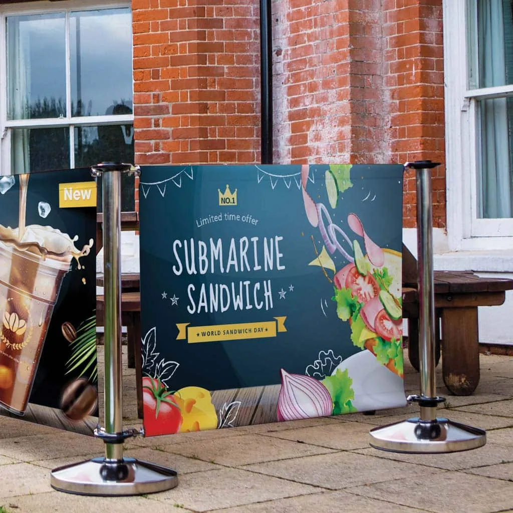 Printed café barrier advertising a submarine sandwich outside a brick-fronted café