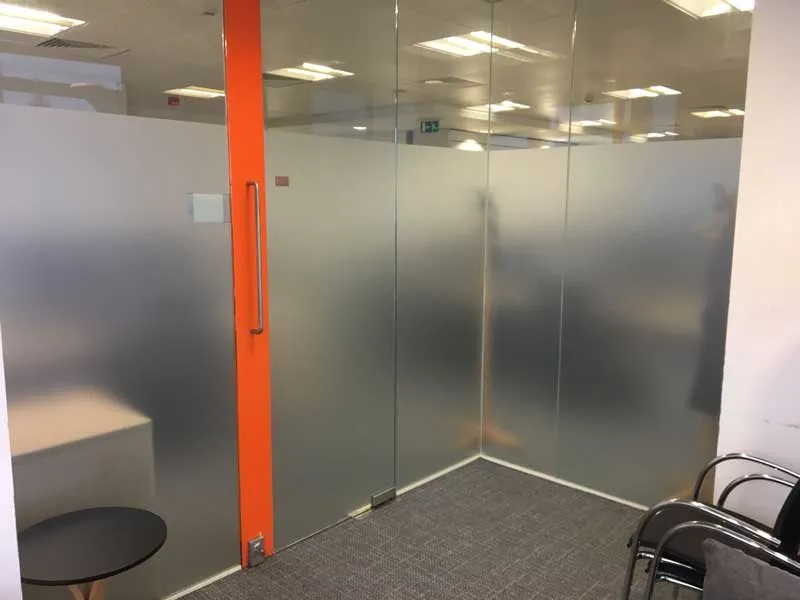 Frosted privacy film applied to a glass office partition beside an orange column