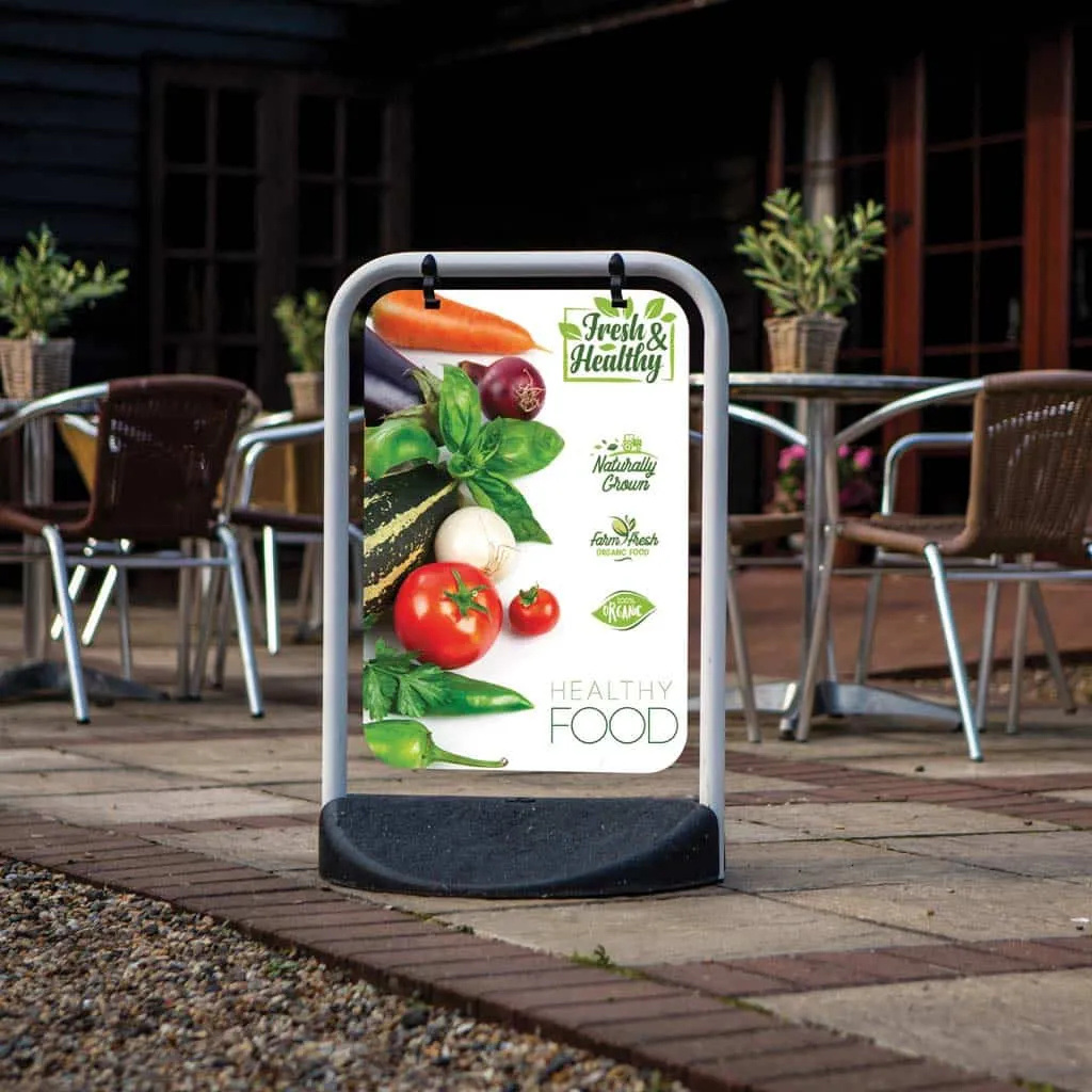 Swing pavement sign advertising healthy food beside a café terrace