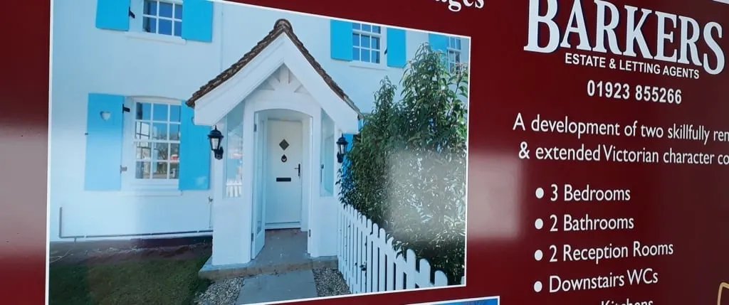 Printed estate agent development board showing a house and a list of rooms