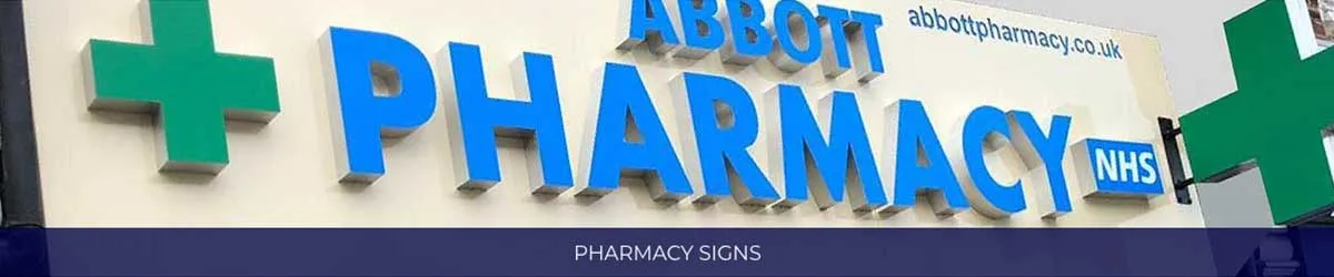 Illuminated blue 3D pharmacy lettering flanked by green crosses and an NHS logo above a shopfront