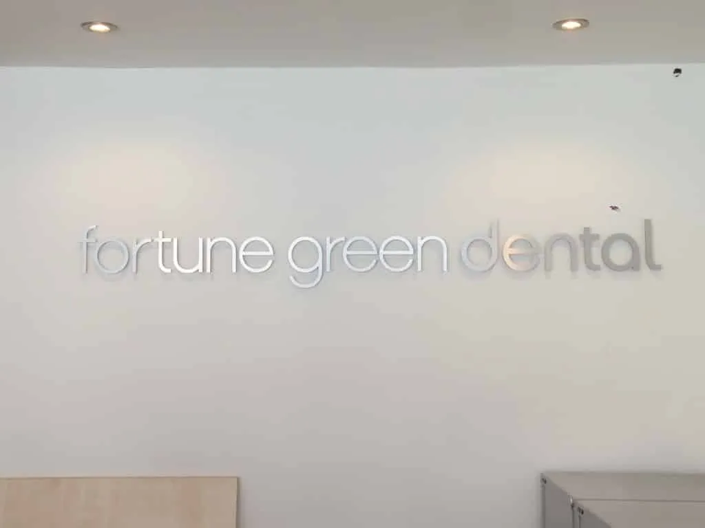 Frosted glass lettering reading fortune green dental on a pale reception wall