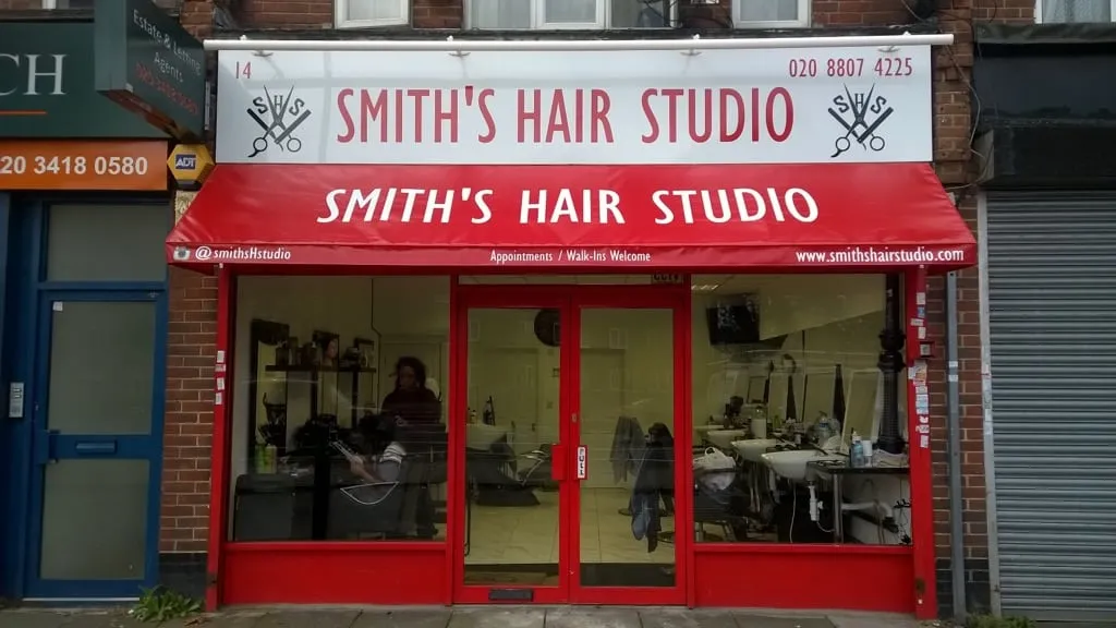 A red fascia sign and matching red awning for Smith's Hair Studio
